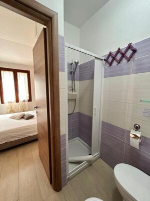 a bathroom with a shower and a toilet and a bed at Villa Lavinia in Alghero