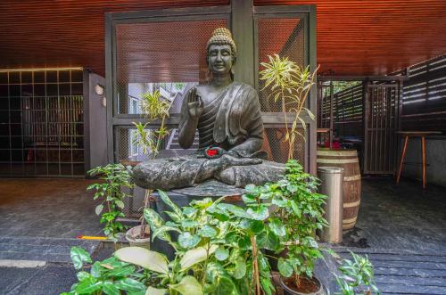 a statue sitting in a room with plants at Open Hotel by Olive - Slate in Chennai
