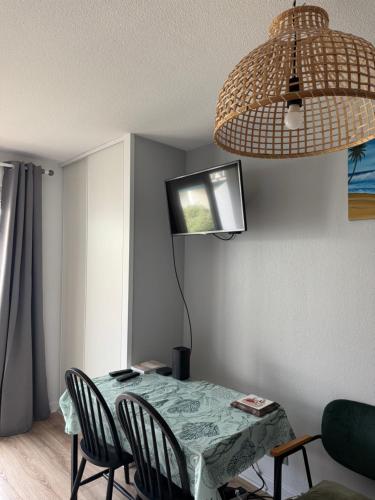 a table with chairs and a television on a wall at Studio dans résidence avec piscine in Bidart
