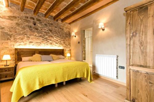 a bedroom with a large bed with a yellow blanket at El Mas de Mateus in Sagás