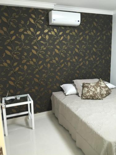 a bedroom with a bed and a black and gold wall at Apartamento Spiaggia Del Sole in Guarujá