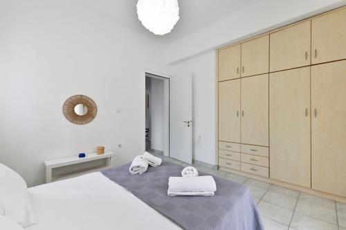 a white bedroom with white towels on a bed at Blue Residences in Paralia Vrachou