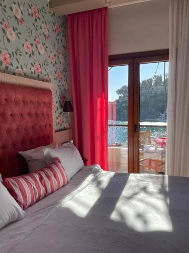 a bedroom with a bed with a red headboard and a window at Olympic Apartments in Parga