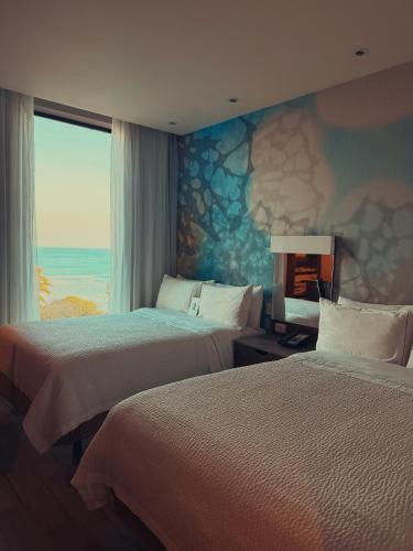 two beds in a hotel room with a view of the ocean at InHouse Ciudad del Carmen in Ciudad del Carmen