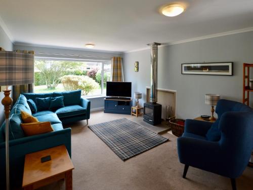a living room with two blue couches and a television at March Brown in Garmouth