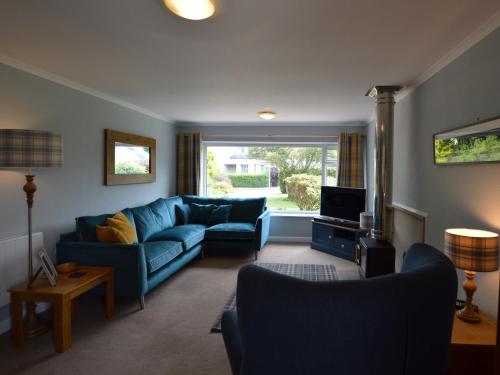 a living room with a blue couch and a television at March Brown in Garmouth