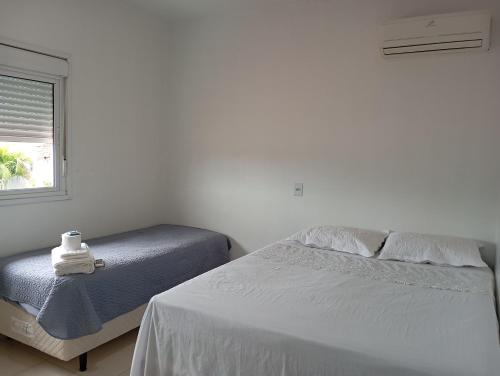 a white bedroom with a bed and a window at Quarto casal in Itaqui