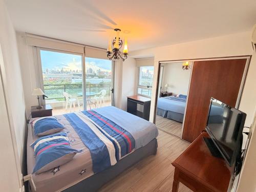 a bedroom with a bed and a television and a balcony at Puerto Amarras Apartment in Santa Fe