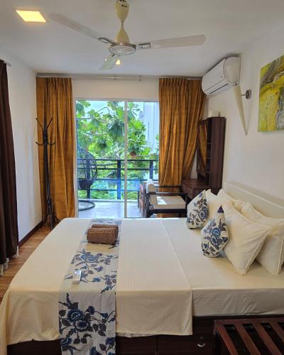 a bedroom with a large bed and a balcony at Daisy Cottage Dhangethi in Dhangethi