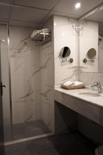 a bathroom with a shower and a sink and a mirror at POST Hotel Amman in Amman