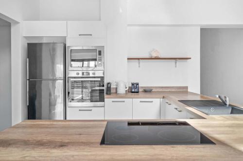 a kitchen with white cabinets and stainless steel appliances at Golden Bloom - High-End Duplex w Private Pool in Rivière Noire