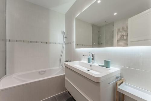 a white bathroom with a sink and a bath tub at Beach Villa Cristina by HHBCN in Castelldefels