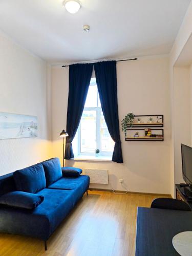 a living room with a blue couch and a window at Studio, Fireplace, Super location, Free Parking in Tallinn