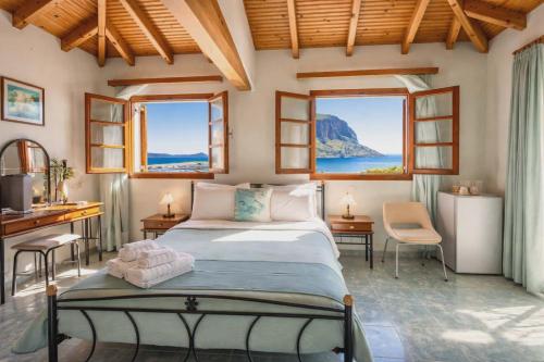 ein Schlafzimmer mit Bett, Schreibtisch und zwei Fenstern in der Unterkunft AGNANTIO in Monemvasia