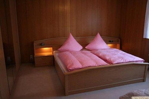 a bedroom with a bed with pink sheets and pillows at Haus-Schneider-grosse-Ferienwohnung in Wolfshagen