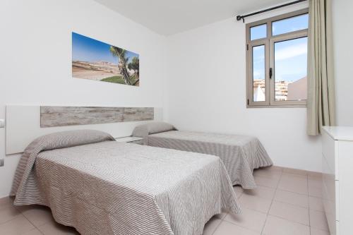 two beds in a room with a window at TAO Morro Jable in Morro del Jable