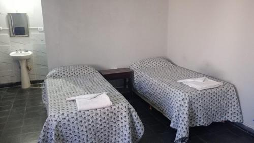 two twin beds in a room with a sink at Posada el circulo in Chamical