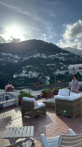 a woman standing on top of a balcony with chairs at Antica Porta Residence, in the center of Ravello, 3 min walk within Villa Rufolo and the main Square in Ravello