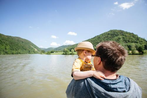 a man holding a child on his back near a lake at Gasthof Gierlinger in Obermühl