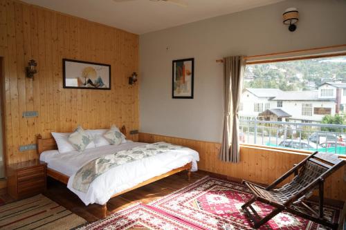 a bedroom with a bed and a window and a chair at The Windbloom - Himalayan Farm Stay in Mukteshwar