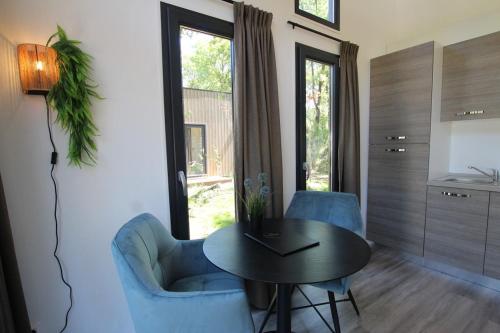 a living room with a table and two blue chairs at Knusse Tiny House in de natuur in Baarle-Nassau