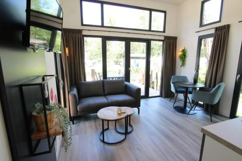 a living room with a couch and a table at Knusse Tiny House in de natuur in Baarle-Nassau