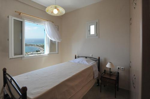 a bedroom with a bed and a window at Veranta Me Thea in Agios Ioannis