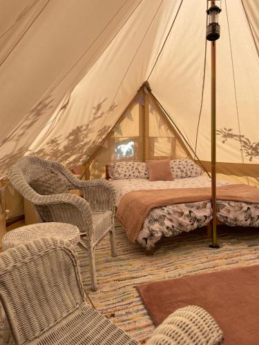 a bedroom with a tent with a bed and chairs at The Apple Farm Glamping in Snitterfield