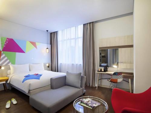 a hotel room with a bed and a chair at Ibis Styles Jakarta Sunter in Jakarta