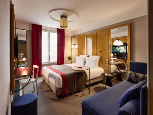 a hotel room with a bed and a couch at l'Echiquier Opéra Hotel Paris - MGallery Collection in Paris