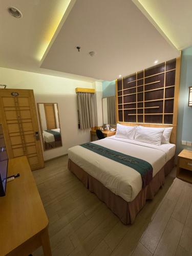 ein Hotelzimmer mit einem großen Bett und einem Schreibtisch in der Unterkunft UNUMA HOTEL in Jakarta