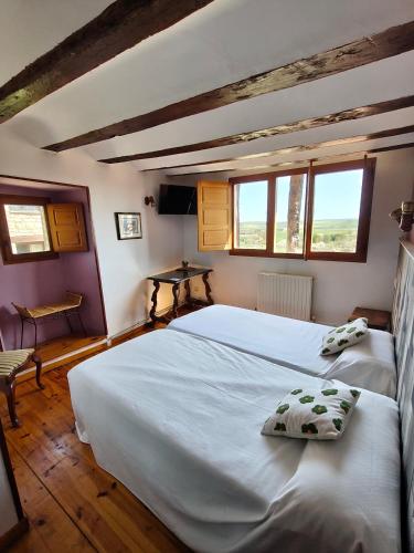a bedroom with two beds and two windows at Hotel Rural Papasol in Atapuerca