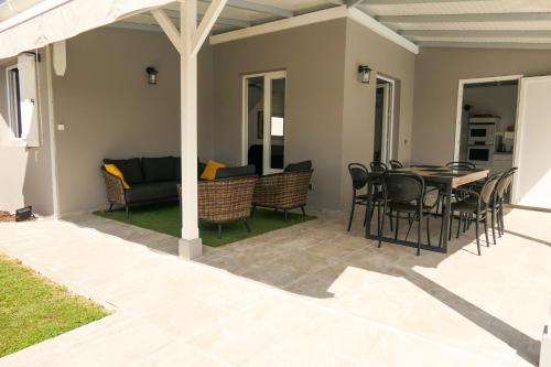 a patio with a table and chairs and a couch at Villa Diams Diamond in Le Diamant