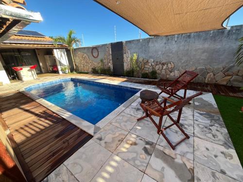 a pool with a chair next to a house at Chalé Mon Amour com sua piscina privativa in São Miguel do Gostoso