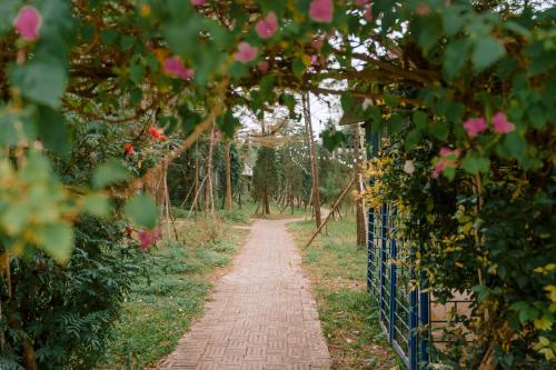 a path through a garden with pink flowers at Veco Pine in Thạch Cầu