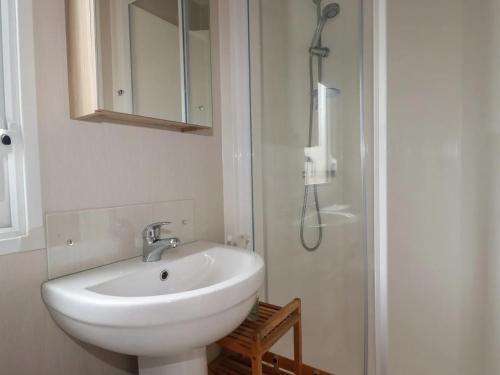 a bathroom with a white sink and a shower at Eth Melyn Caravan Holiday in Grampound