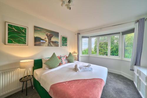 a bedroom with a large bed and two windows at Spacious 4-Bedroom House in High Wycombe with Parking Fast WiFi in Buckinghamshire