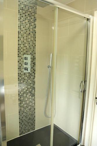 a shower with a glass door in a bathroom at Luxury Heathrow Modern House with Parking & Fast WiFi in Northolt