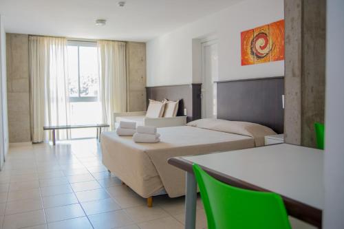 a hotel room with two beds and a table and chairs at Torre Potosi Departamentos in Rosario