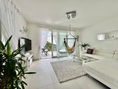 a white living room with a couch and a tv at Villa 124 Residence in Lignano Sabbiadoro