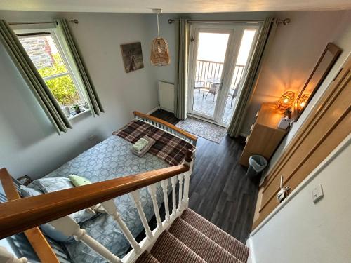 a room with a bed and a staircase with two windows at Looe, Cornwall, couples, families, quiet location, views, reliable Wi-Fi, 3 bed LANGUNNETT COTTAGE in Looe