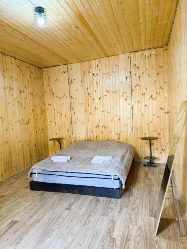 a bedroom with a bed in a wooden room at racha cozy cottage in Ambrolauri