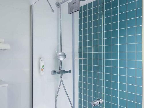 a bathroom with a shower with blue tiles at ibis Styles Deauville Centre in Deauville