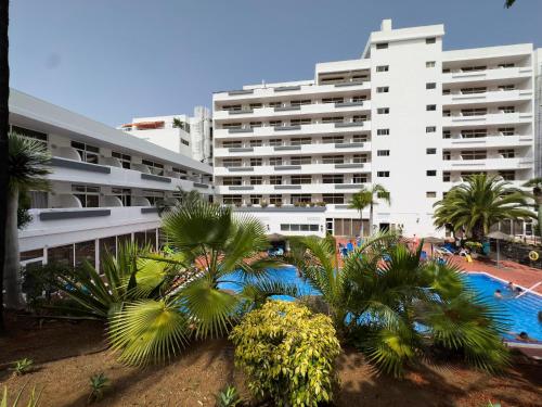 a large white building with a swimming pool and palm trees at Complejo BLUESEA Puerto Resort compuesto por Hotel Canarife y Bonanza Palace in Puerto de la Cruz