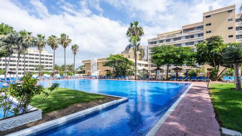 a swimming pool at a resort with palm trees and buildings at Complejo BLUESEA Puerto Resort compuesto por Hotel Canarife y Bonanza Palace in Puerto de la Cruz