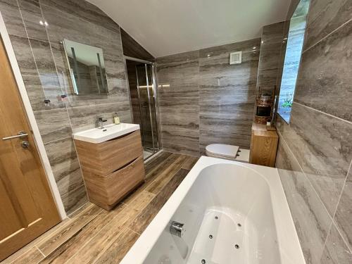 a bathroom with a tub and a toilet and a sink at Looe, Cornwall, couples, families, quiet location, views, reliable Wi-Fi, 3 bed LANGUNNETT COTTAGE in Looe