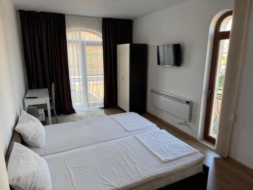 a bedroom with two beds and a television on the wall at Panoramic Sea View Apartment in Byala