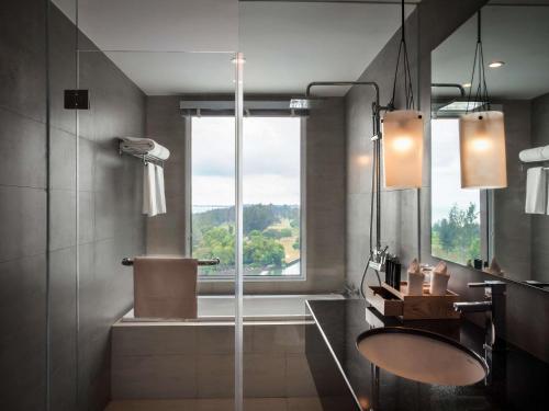 a bathroom with a shower and a sink and a window at Pullman Miri Waterfront in Miri