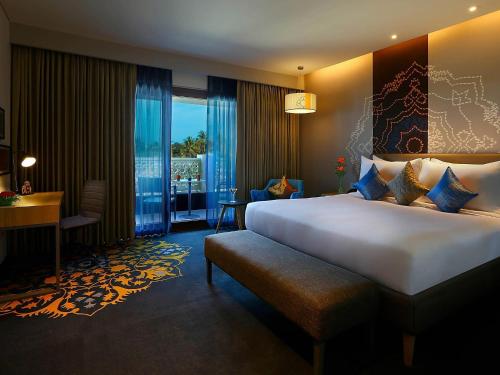 a hotel room with a large bed and a desk at Grand Mercure Mysore - An Accor Brand in Mysore