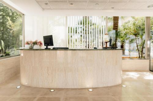a lobby with a reception desk with a large window at BLUESEA Paraiso Beach - Adults Only in Es Cana